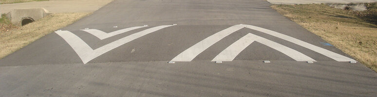 A rounded traffic calming device on top of a road, with the intention to slow down cars. Also called speed bump.